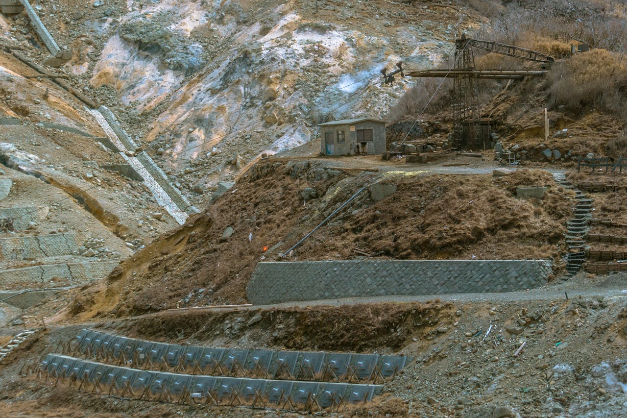 An abandoned industrial mining area featuring rugged terrain and an old crane structure.